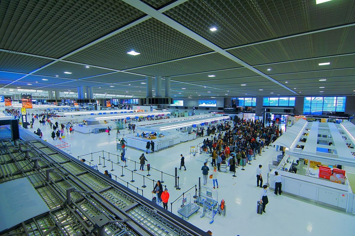 Wide view of the busy departure lobby at Narita Airport Terminal 2 with check-in counters and travelers lining up