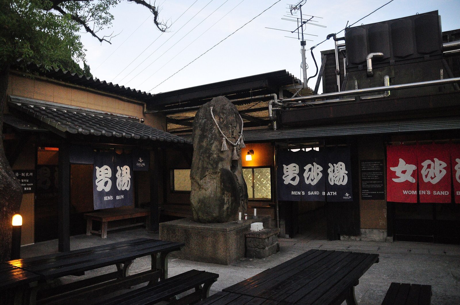 Entrance to Hyotan Onsen in Beppu, Oita, with a dark noren curtain marked for men and a red noren curtain marked for women