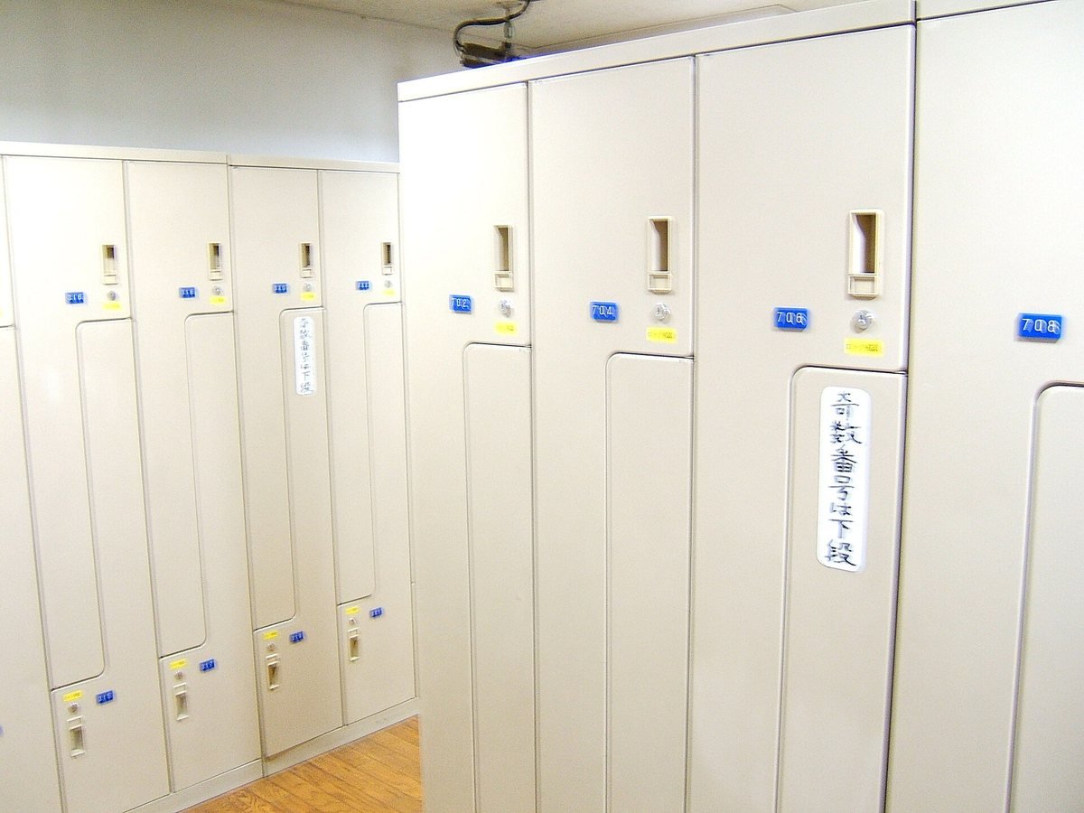 Rows of tall white numbered lockers in the locker room of a capsule hotel in Akihabara, Tokyo