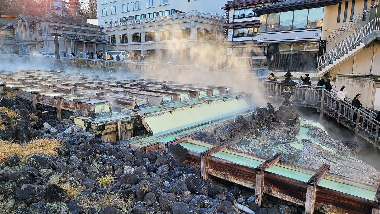 Steam rising from the Yubatake hot water field in the centre of Kusatsu Onsen, Gunma, with wooden channels and surrounding inns