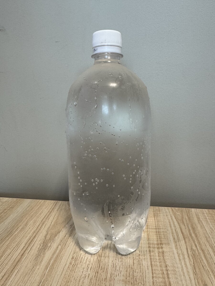 Clear 7-Eleven Japan sparkling water PET bottle with white cap and condensation on a desk