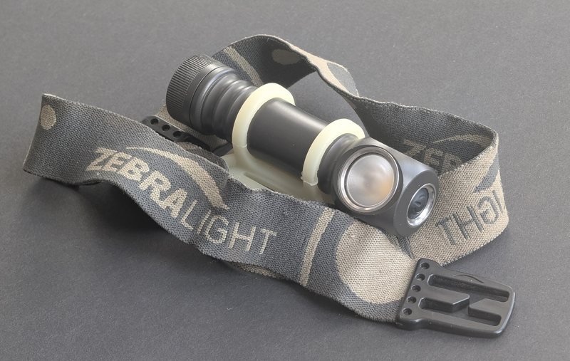 A compact LED headlamp with an elastic headband on a grey background (item type photo, not the exact product)