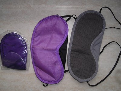 Three fabric sleep masks in purple and grey laid out on a table (item type photo, not the exact product)
